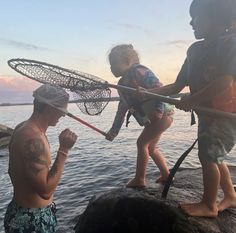 two young boys and an adult are fishing on the water