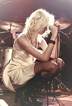 a woman sitting on top of a chair in front of a drum kit and microphone