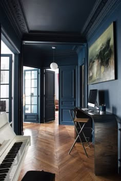 an empty room with a piano, desk and chair in it's center area