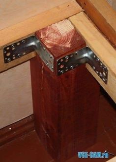 the corner of a wooden table with metal brackets on it's sides and bottom