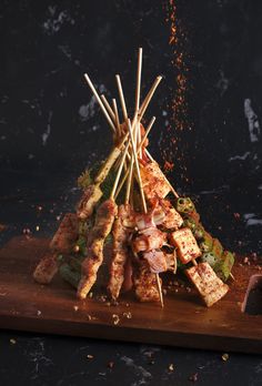 skewers of meat and vegetables on a cutting board with spices scattered around them