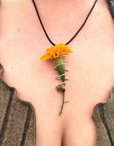 a woman wearing a necklace with an orange flower attached to it