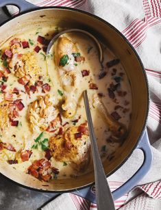 a skillet filled with chicken and cheese covered in gravy next to a spoon