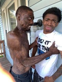 two men standing next to each other in front of a house with mud on their body