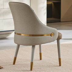 a beige chair with gold trim around the legs and back rests on a carpeted floor