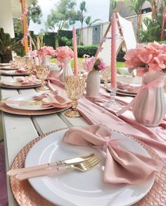 the table is set with pink flowers and gold place settings for an elegant dinner party