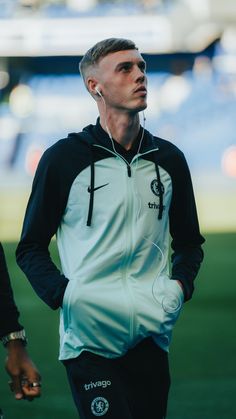 a man with ear buds standing on a soccer field