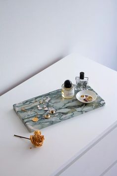 a marble tray with two bottles on it and a rose sitting next to the plate