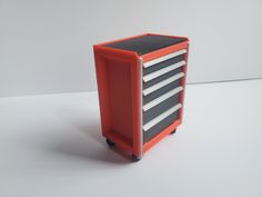 an orange and black tool box on wheels with five drawers in the middle, sitting on a white surface