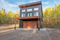 a two story house in the middle of a wooded area with an attached deck and garage