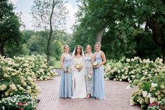 three bridesmaids pose for a photo in front of flowers