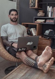 a man sitting in a chair with his feet up on the table while using a laptop