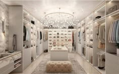 a walk - in closet with an ottoman and chandelier hanging from the ceiling