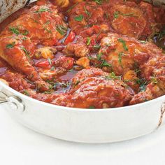 a large pot filled with meat covered in sauce and garnished with parsley