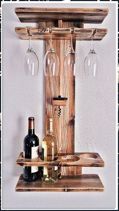 a wooden shelf with wine glasses and bottles hanging from it's sides on the wall