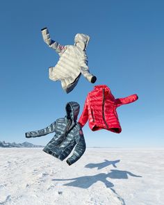 three kites are flying in the sky above some snow covered ground and one is upside down