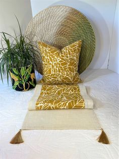 two pillows and a plant on a bed