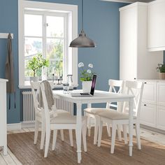 a dining room with blue walls and white furniture