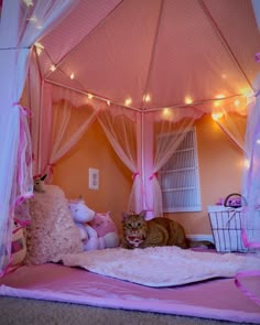 a cat laying on top of a bed covered in pink sheets and curtains with fairy lights