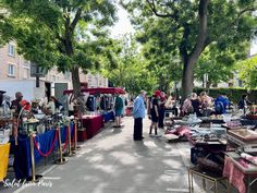 an outdoor flea market with people looking at items on tables and vendors lined up along the sidewalk