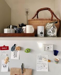 a white refrigerator freezer sitting next to a shelf filled with cups and mugs