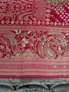 a red and gold cloth with intricate designs on the edges is sitting on a table