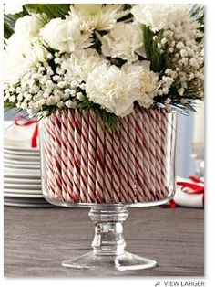 a christmas centerpiece with white flowers and red and white candy canes in it