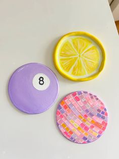 three pieces of art made to look like lemons and a pool ball on a table