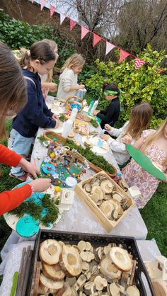 children are gathered around a table with food on it and buns in the middle