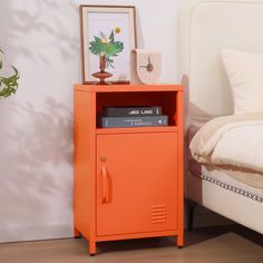 an orange cabinet next to a bed with a plant on top and a clock above it