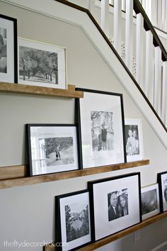 some pictures are hanging on the wall next to a stair case and framed photos in black and white