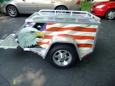 an eagle painted on the side of a trailer in front of parked cars and trees