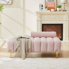 a pink couch sitting in front of a fireplace with a blanket on it's back