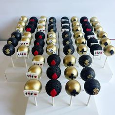 there are many black and gold cake pops with red hearts on them, as well as other decorations