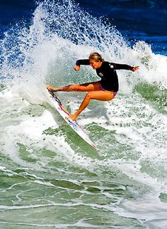 a woman riding a wave on top of a surfboard