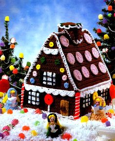 a crocheted gingerbread house is shown in the snow with candy decorations around it