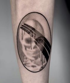 a man's leg with a black and white tattoo on it, depicting an eye in the sky