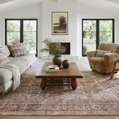 a living room with couches, chairs and a coffee table in front of two windows