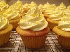 cupcakes with white frosting and yellow sprinkles on a cooling rack