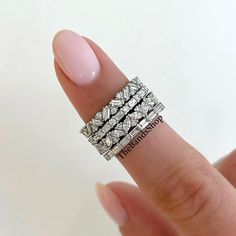 a woman's hand with three rings on top of her finger and the ring has four rows of diamonds