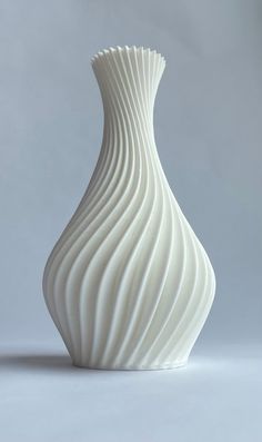 a white vase sitting on top of a table next to a gray wall and floor