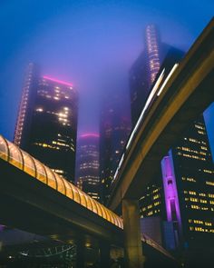 the city skyline is lit up at night, with skyscrapers in the background and foggy skies