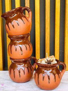 three clay pots with chocolate drizzled on them sitting next to each other