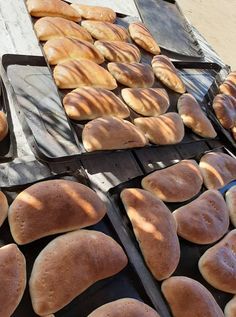 breads are lined up on trays in the sun, ready to be baked