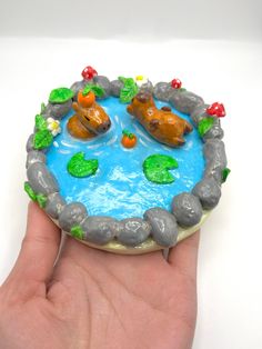 a hand is holding a small toy pond