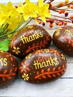 four painted rocks with words on them sitting next to some flowers and yellow daffodils