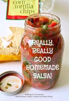 a jar filled with food sitting next to a bag of tortilla chips on top of a table