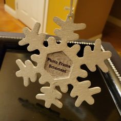 an ornament hanging from a metal tray with snowflakes attached to it