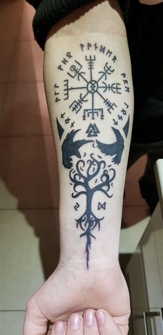 a person with a tattoo on their arm holding up his hand to show the compass