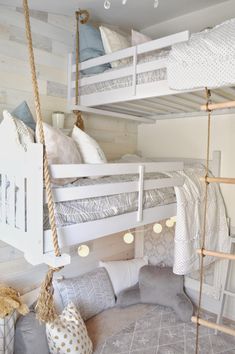 a bunk bed with two sets of ladders hanging from the ceiling and pillows on the floor